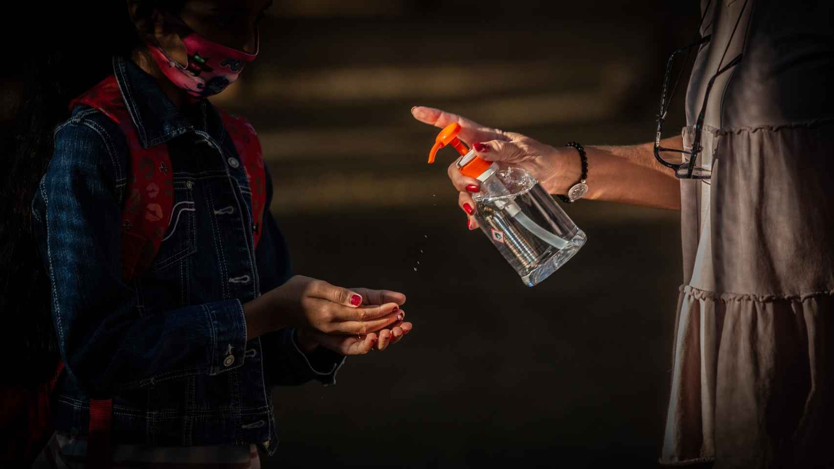 Una profesora administra gel desinfectante a un alumno en un colegio en Barcelona, Cataluña.