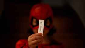 Un niño disfrazado de Spiderman muestra un test de antígenos de resultado negativo en su casa del concello coruñés de Pontedeume.