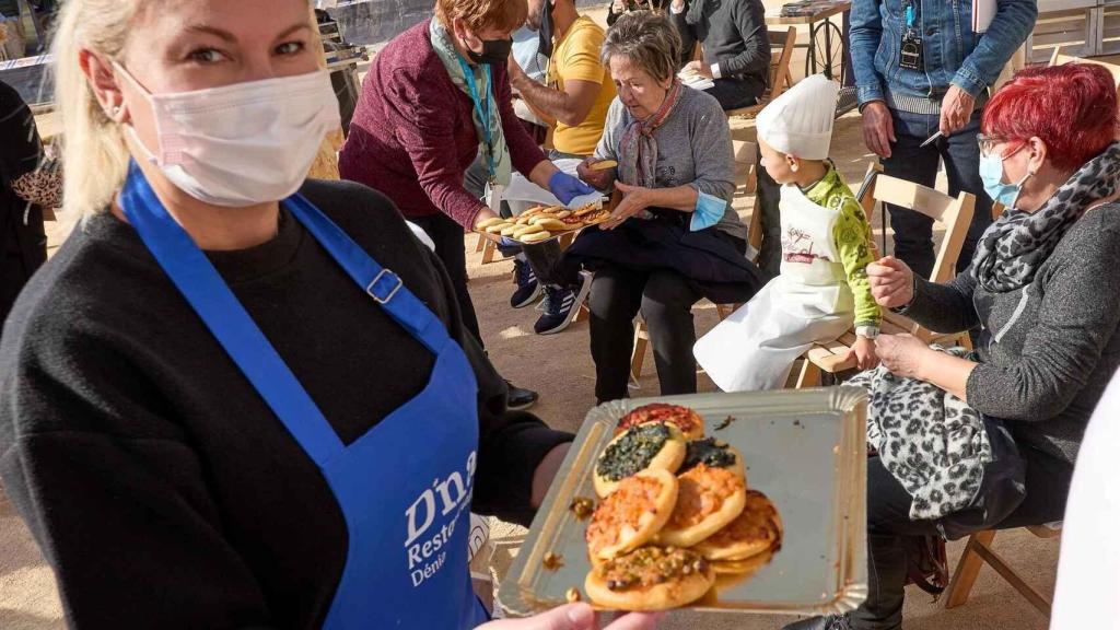 Una mujer reparte las típicas Cocas de la Marina durante el Festival Gastronómico de Dénia 2021.