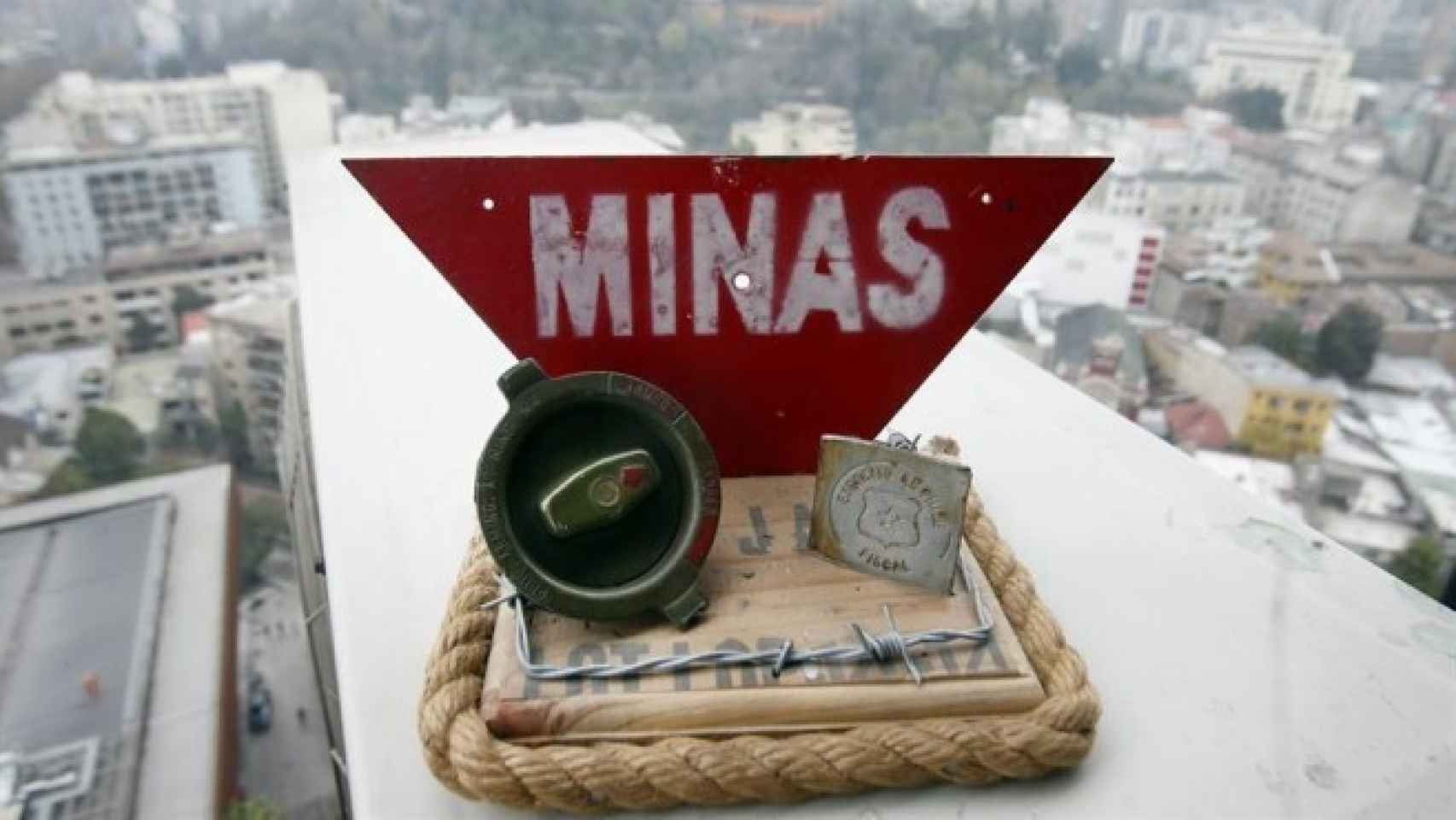 Vista de una maqueta con partes de una mina antipersona y una señal de advertencia.