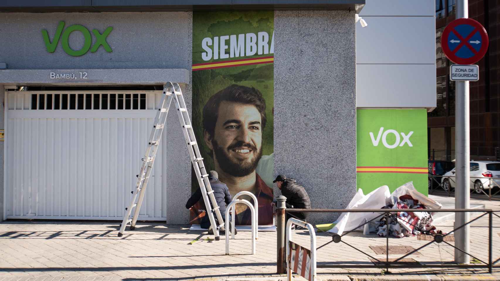 Operarios colocan el cartel con la cara de Juan García-Gallardo en la sede de Vox en Madrid.