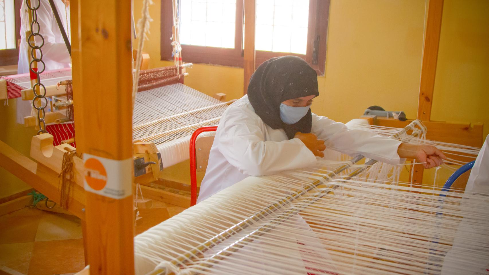 Una mujer tejiendo mandiles.