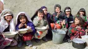 Un grupo de niños afganos reciben alimentos del programa de Naciones Unidas en el campamento de desplazados cerca de Herat.