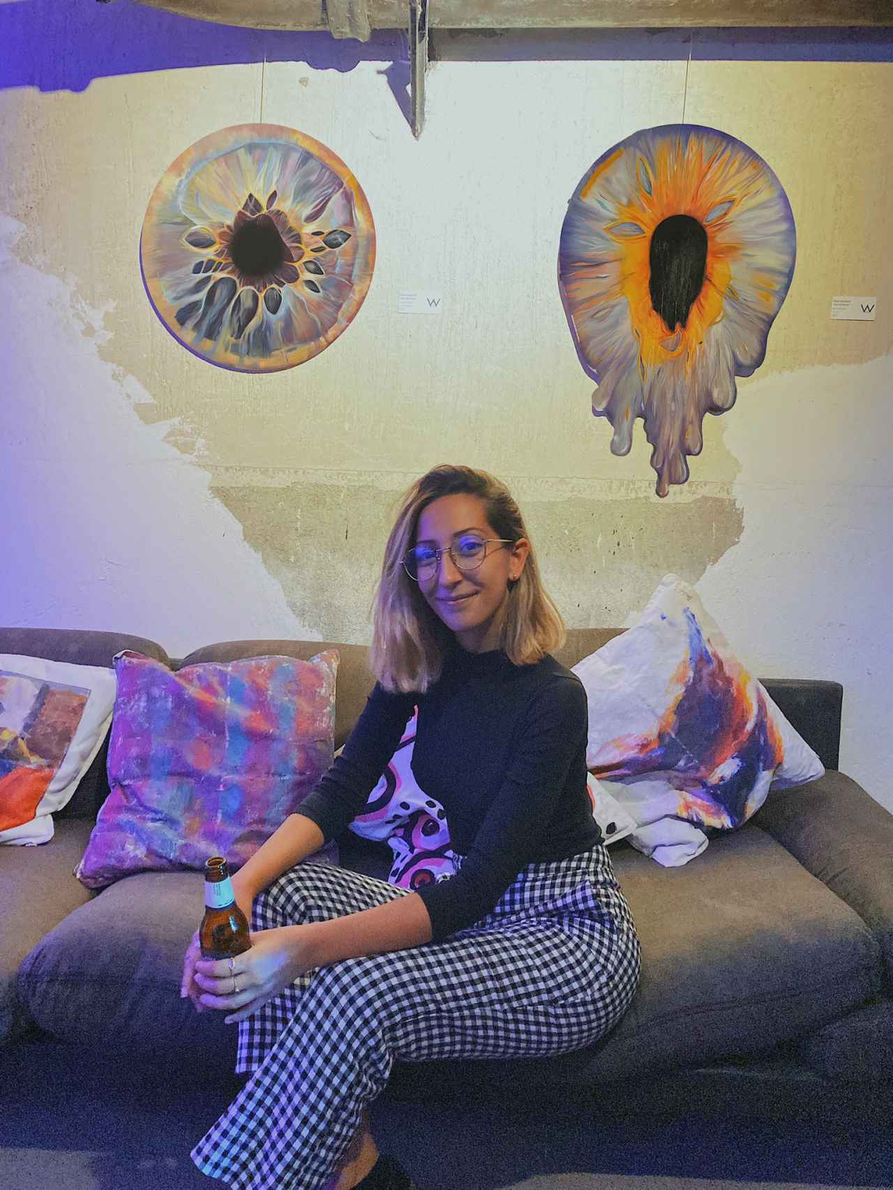 Celia Gallego con dos de sus cuadros (a la derecha uno de los ojos derretidos) en una exposición