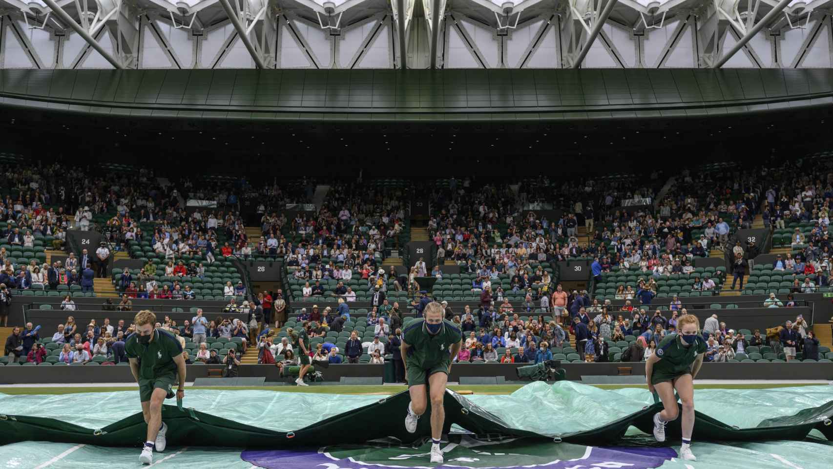 Operarios descubren la pista central del All England Club en Wimbledon