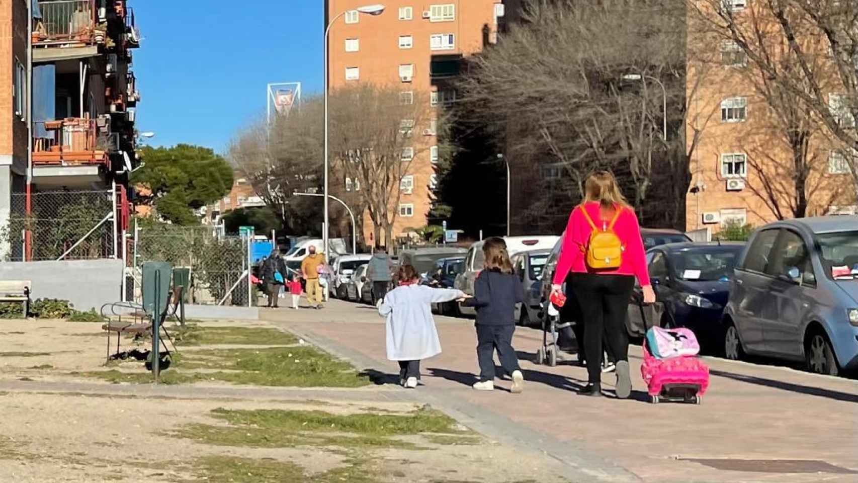 Una mujer pasea junto a sus hijas a la hora de la salida de la escuela.