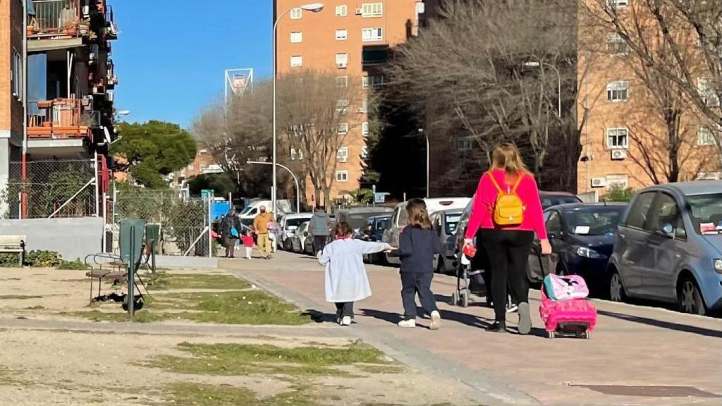 Una mujer pasea junto a sus hijas a la hora de la salida de la escuela.