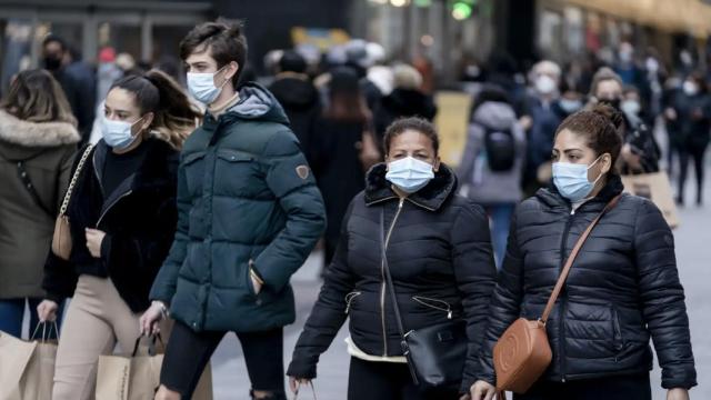 Personas paseando con mascarillas.