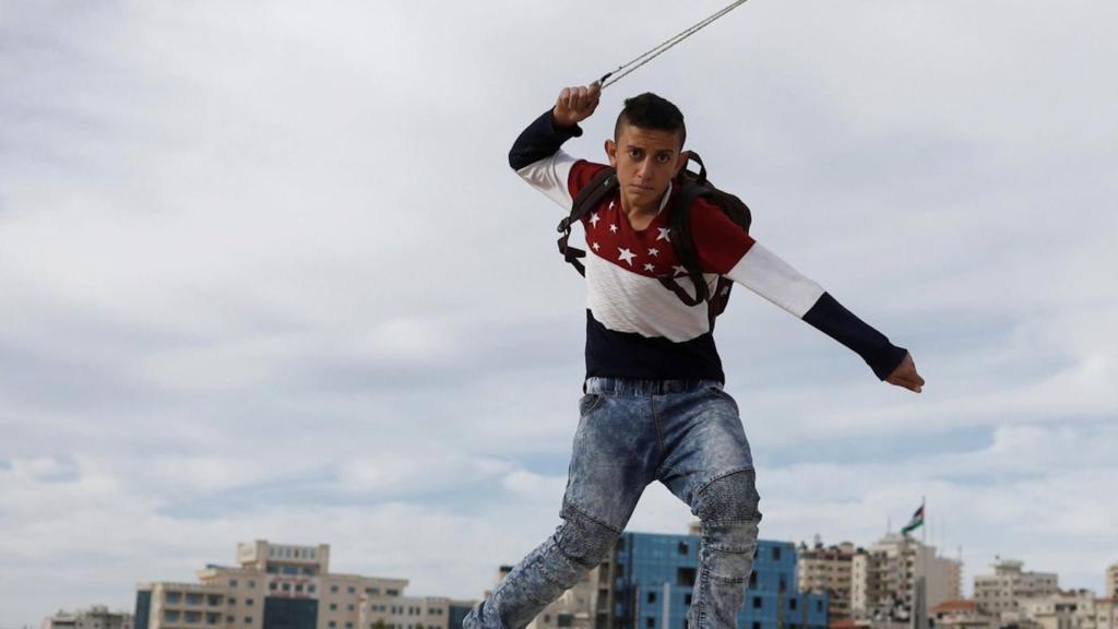 Un palestino arroja piedras contra soldados israelíes durante una protesta en un asentamiento de Cisjordania.