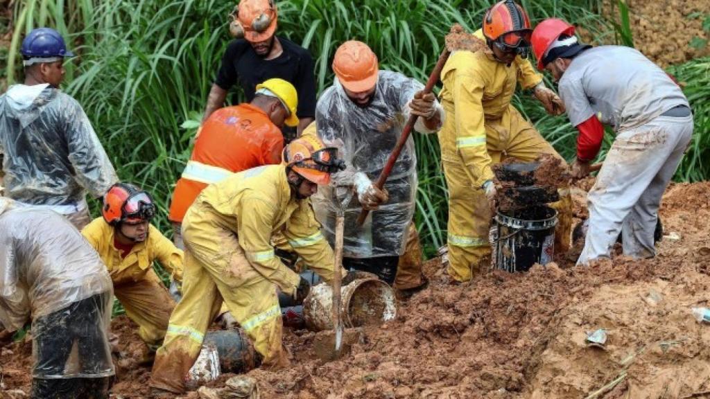 Bomberos y voluntarios trabajan en el área de un deslizamiento de tierra.