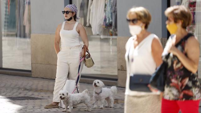 Personas sin mascarilla y otras con mascarilla en la calle Larios,