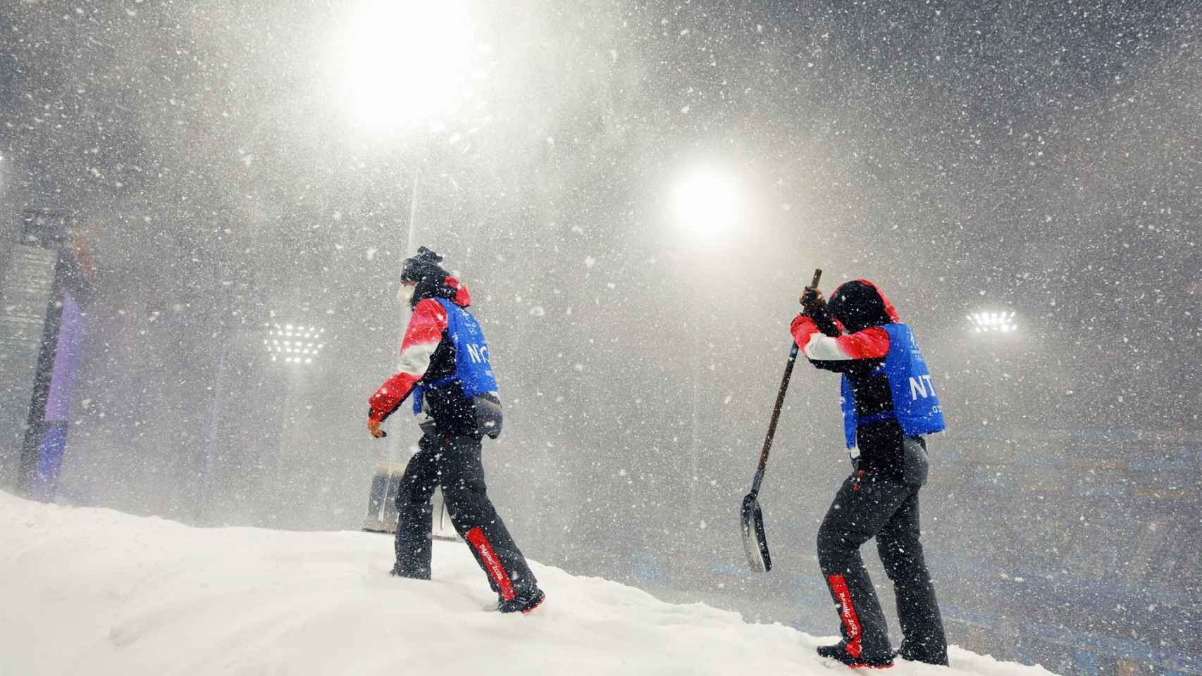 Trabajadores de los Juegos Olímpicos de Invierno de Pekín 2022 quitando nieve