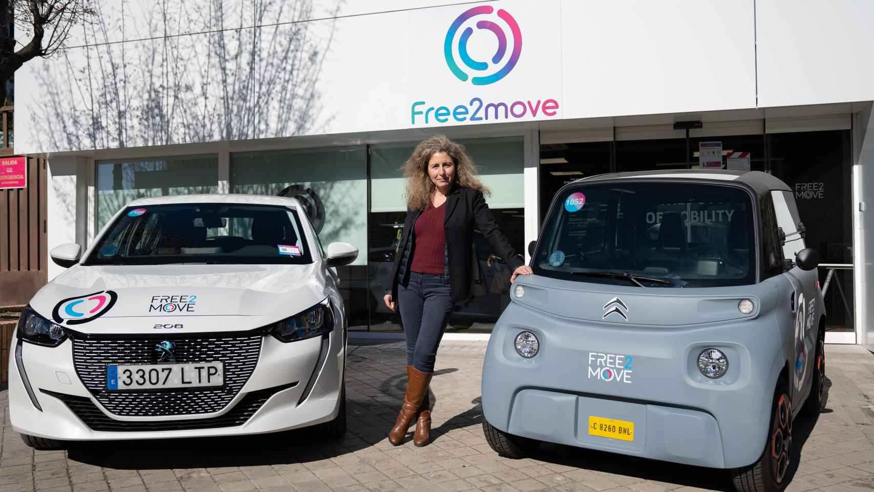 Brigitte Courtehoux junto a los coches con los que opera Free2move en España: un Peugeot 208 y un Citroën Ami, ambos eléctricos.