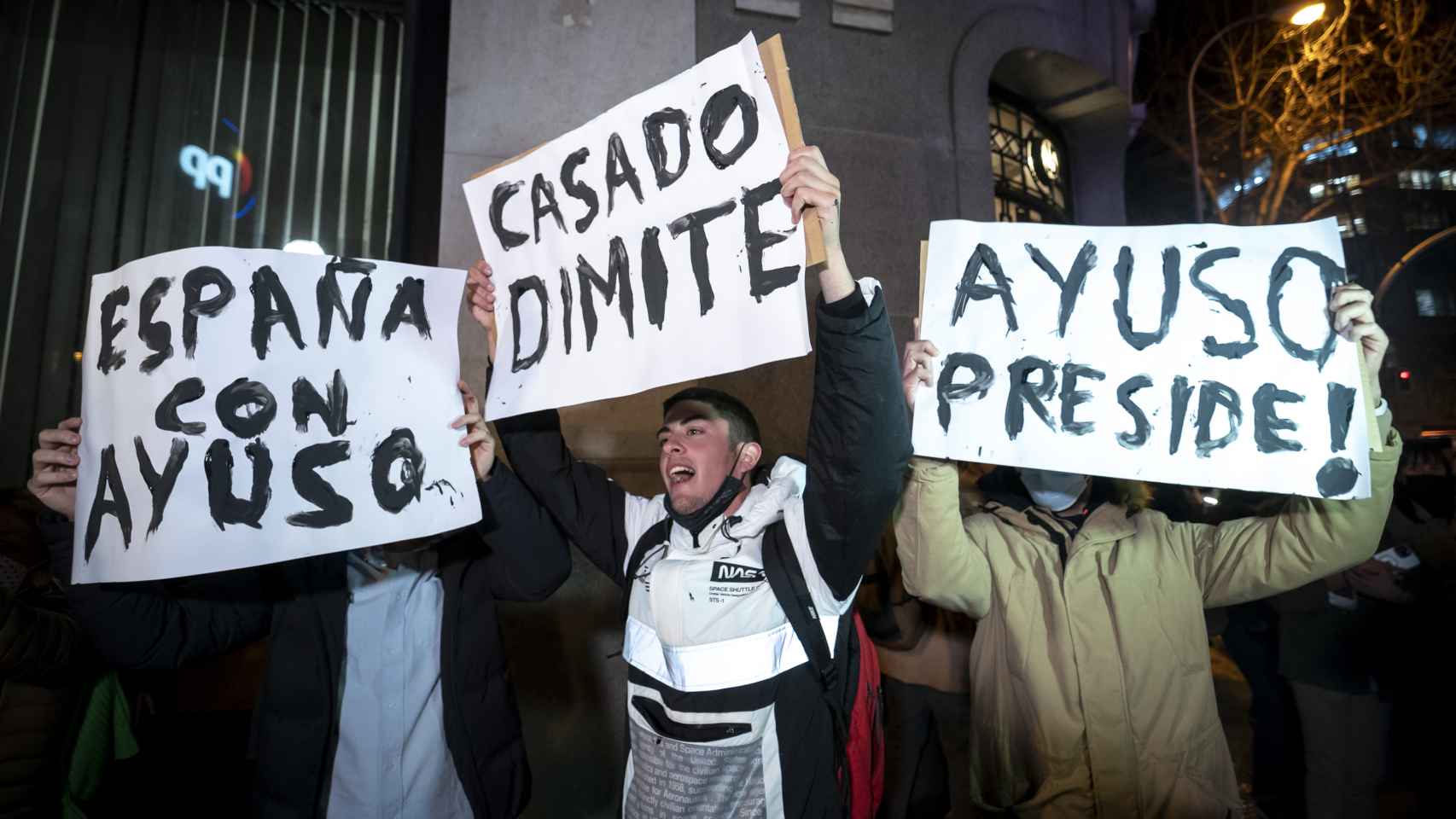 Varias personas sostienen pancartas durante una manifestación en apoyo a la presidenta de la Comunidad de Madrid, Isabel Díaz Ayuso, frente de la sede del Partido Popular en la calle Génova, a 17 de febrero de 2022, en Madrid (España).
