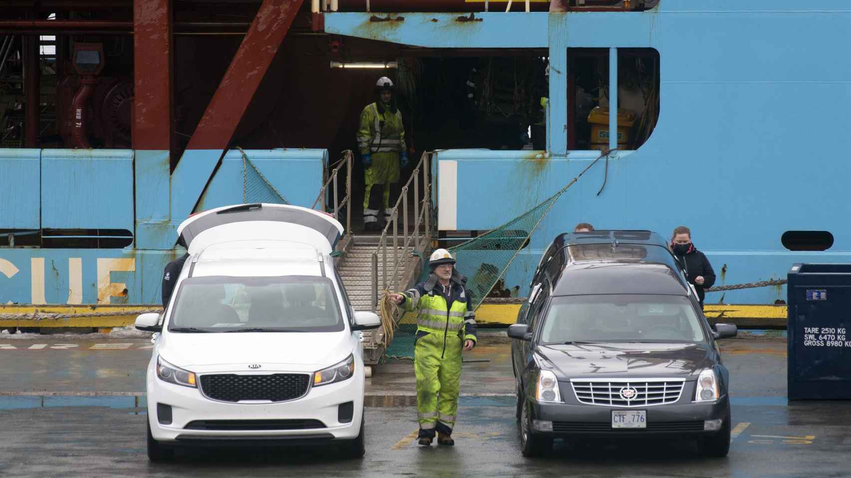 Personal portuario supervisa en Terranova los coches fúnebres donde serán trasladados los cuerpos de los dos pescadores naufragados.