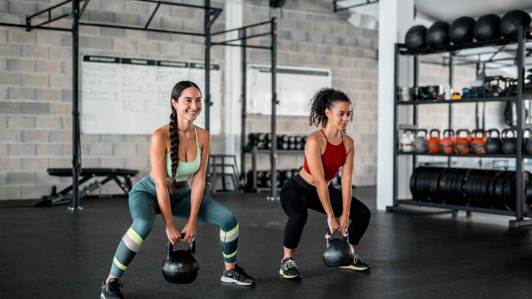 Mujeres haciendo deporte con kettlebells en el gym.