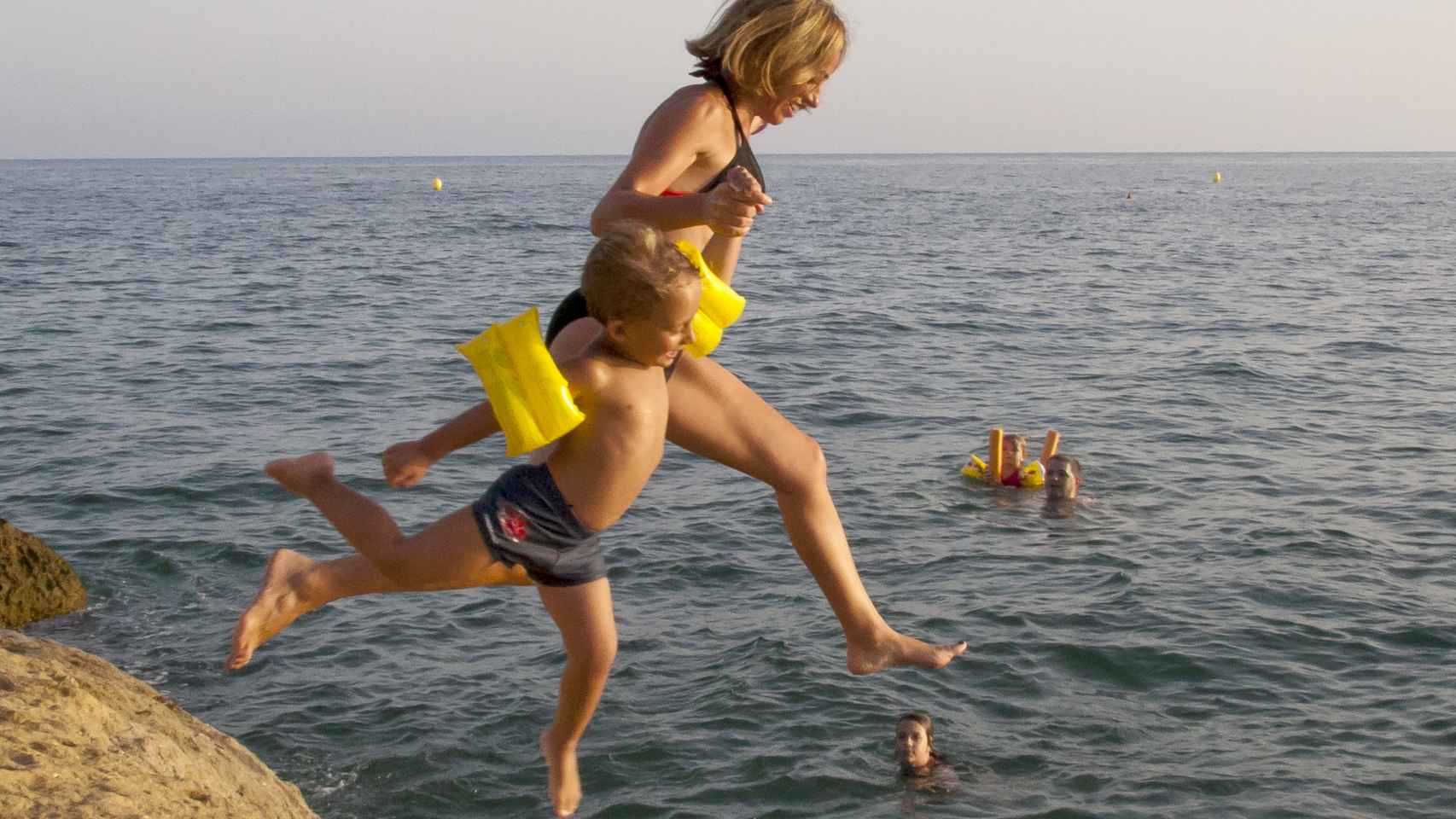 Carme salta al mar de la mano de su hijo Miquel en la playa del Rincón de los Nidos, en San Juan de los Terreros.