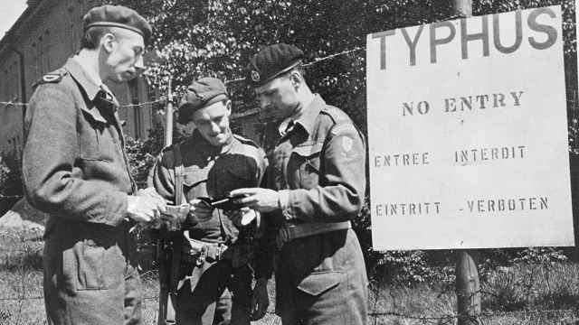 Soldados británicos en 1945, junto a un cartel que advierte que la entrada al campo de concentración de Bergen-Belsen (Alemania) está prohibida por una epidemia de tifus.