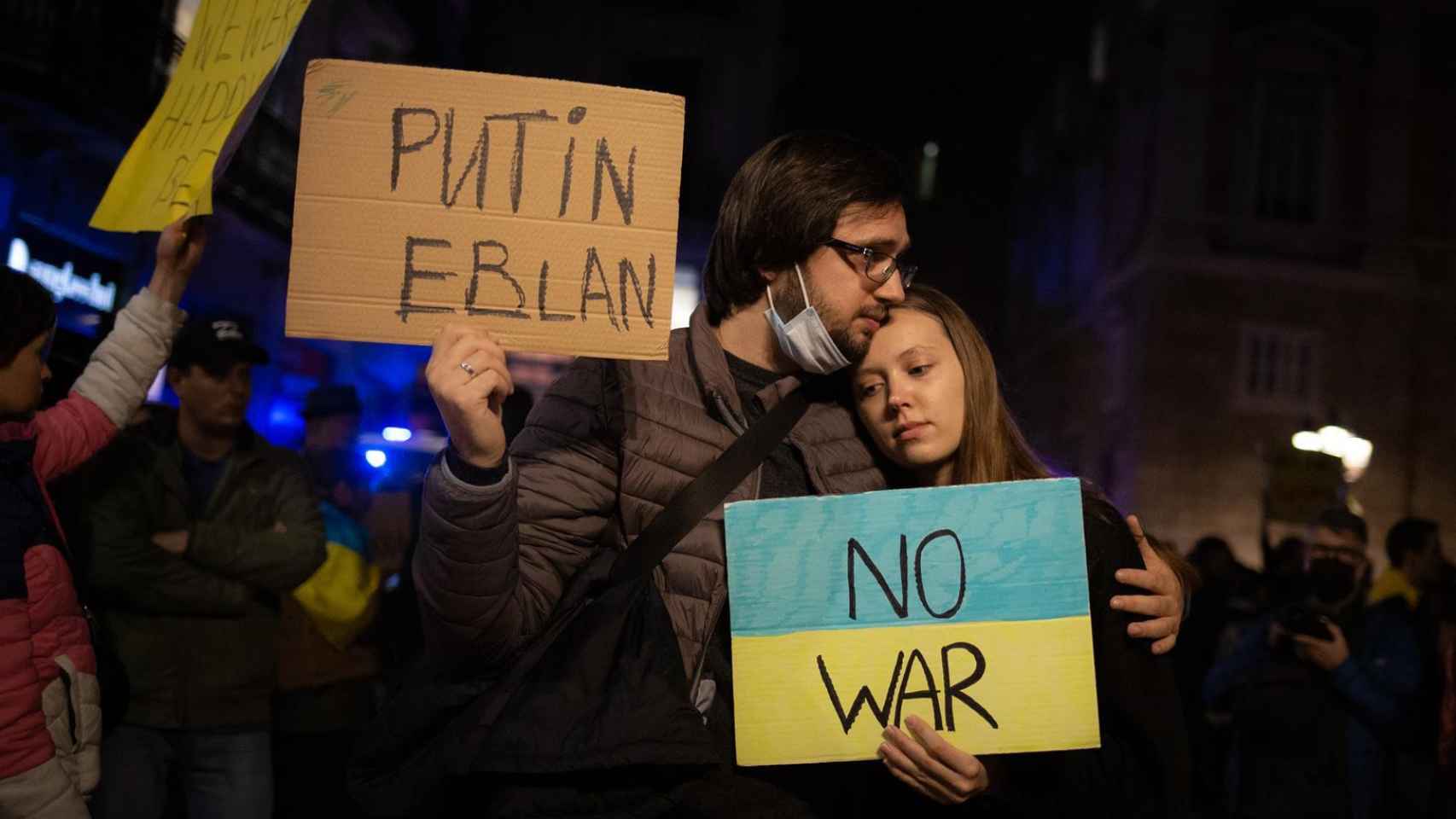 Varias personas sostienen pancartas en una concentración ante la embajada rusa en Barcelona tras los primeros ataques rusos registrados en Ucrania