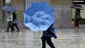 El viento rompe el paraguas de una persona que camina por la calle.