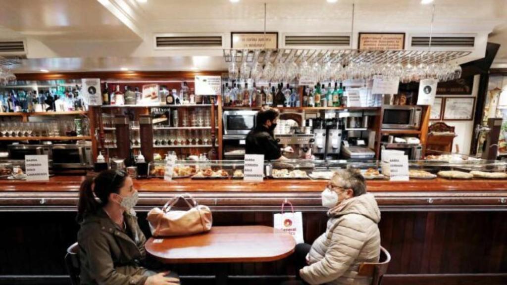 Dos personas en la barra de un bar sentadas y con mascarilla. Efe