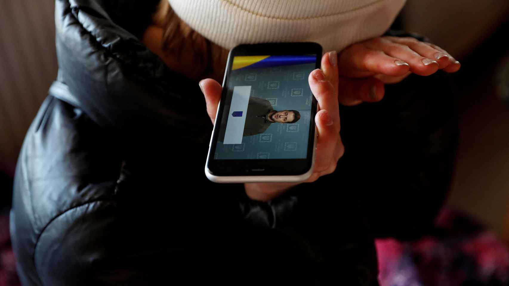 Un refugiado escucha a través de su teléfono móvil la intervención del presidente de Ucrania, Volodimir Zelenski.