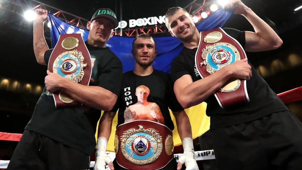 Oleksandr Usyk, a la izquierda, y Vasyl Lomachenko, en el centro, como campeones mundiales