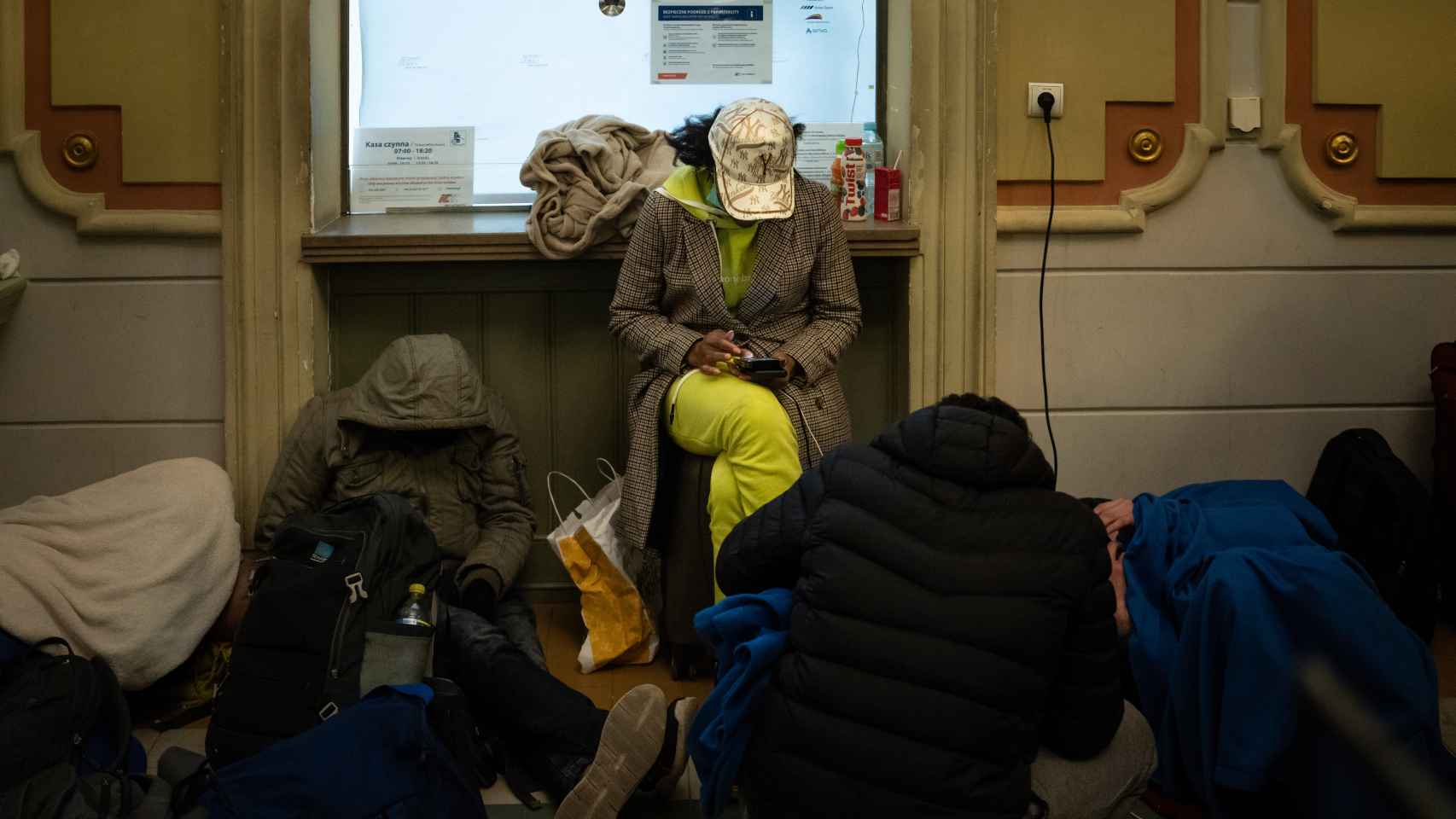 Tras recibir mantas, comida e internet, una estudiante mira el mapa de Europa mientras su compañero duerme en el interior de la estación.