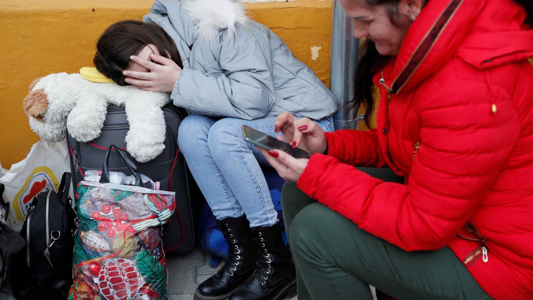 Una mujer procedente de Ucrania consulta su teléfono móvil junto a una niño en el refugio de Beregsurány (Hungría)