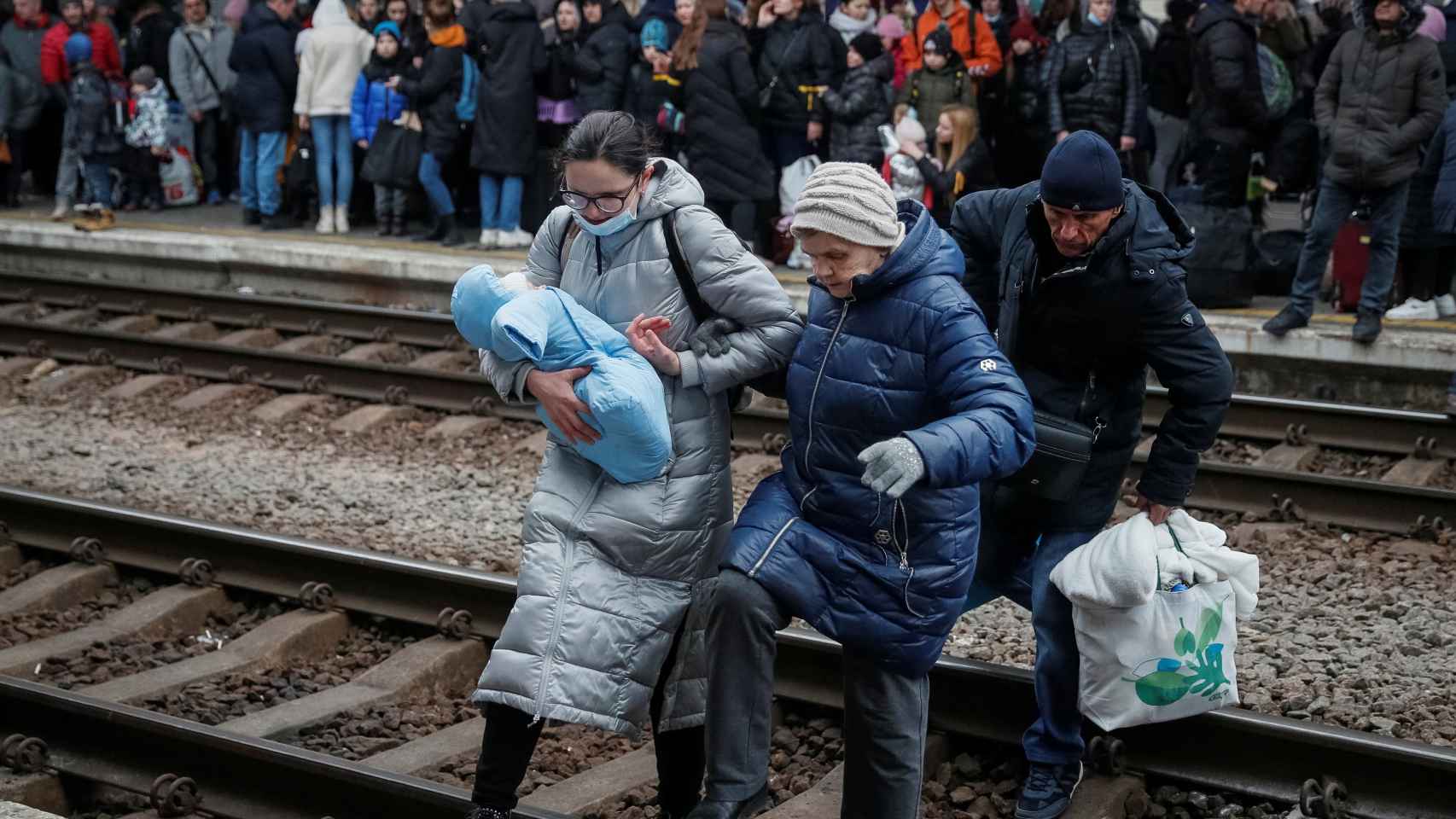 Civiles caminan sobre las vías de la estación principal de Kiev para cambiar de andén e intentar subirse a un tren.