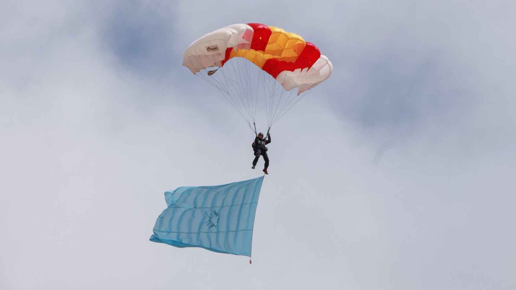 Un paracaidista militar portando una bandera.