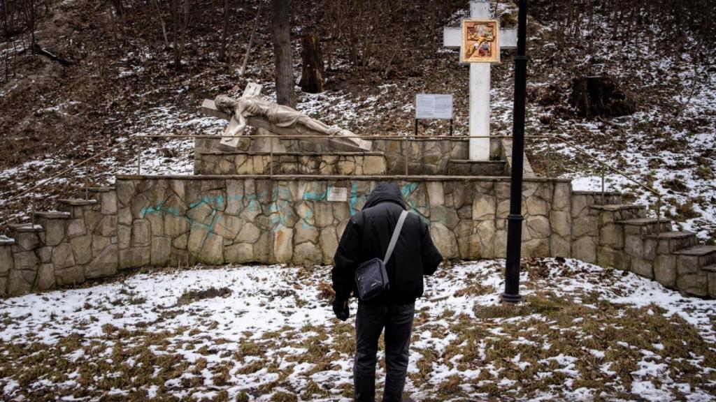 De camino al trabajo, un hombre se detiene a rezar ante la figura de Cristo en la cruz.