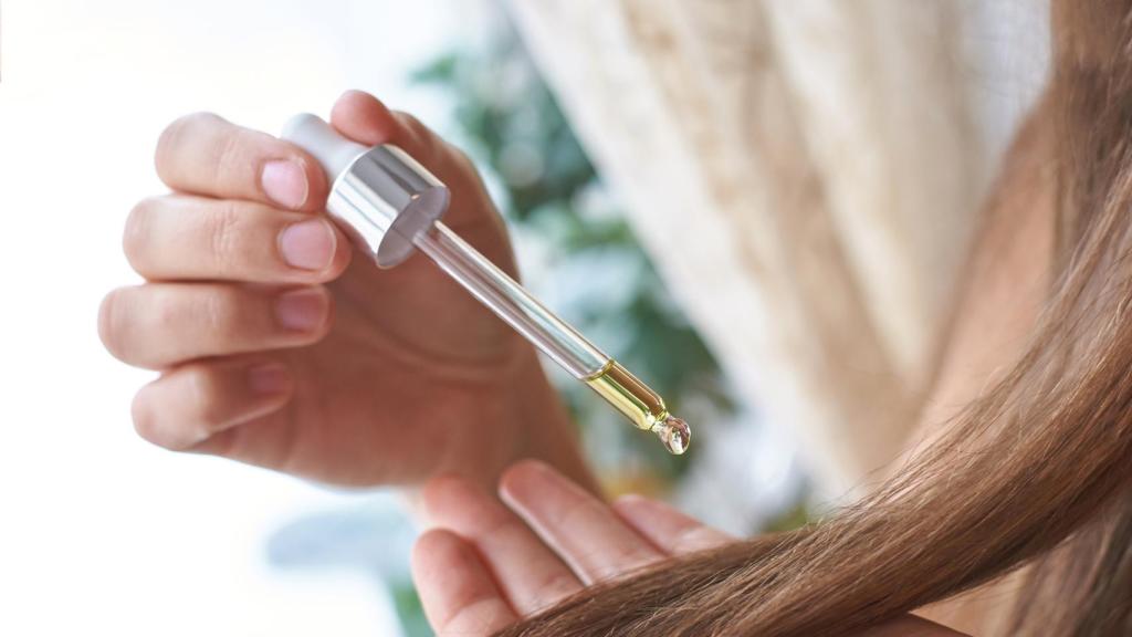 Una mujer aplica una gota de aceite en el pelo
