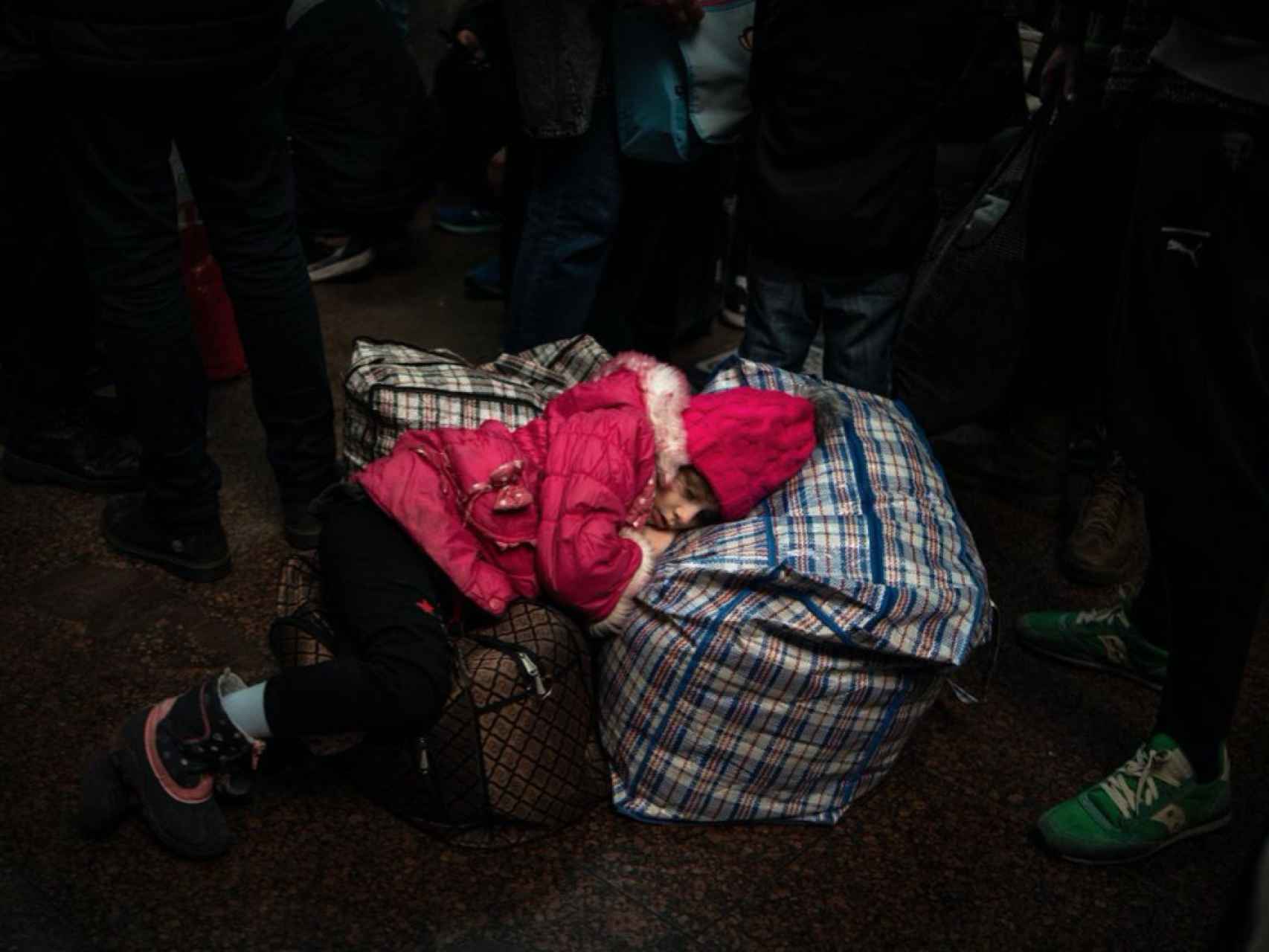 Una niña duerme mientras su familia aguarda al aviso en pantalla del próximo tren.