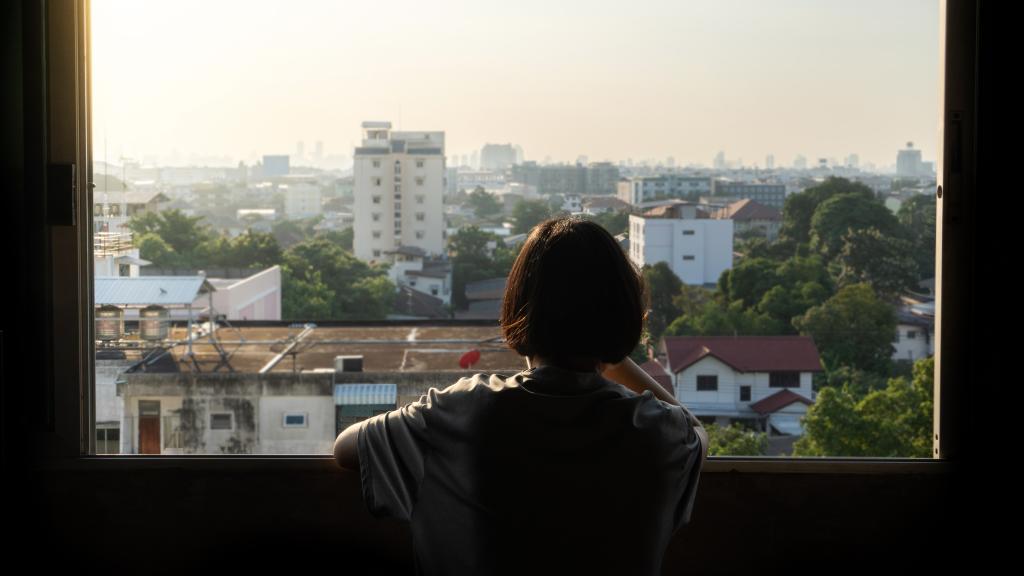 Imagen de archivo de una joven mirando por la ventana.