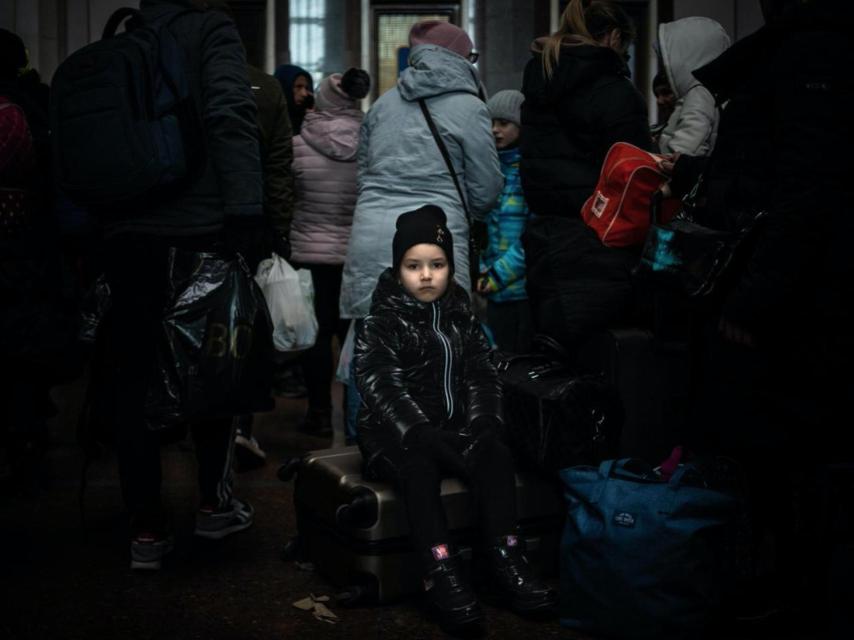 Una menor sobre una maleta en la estación ucraniana de Lviv.