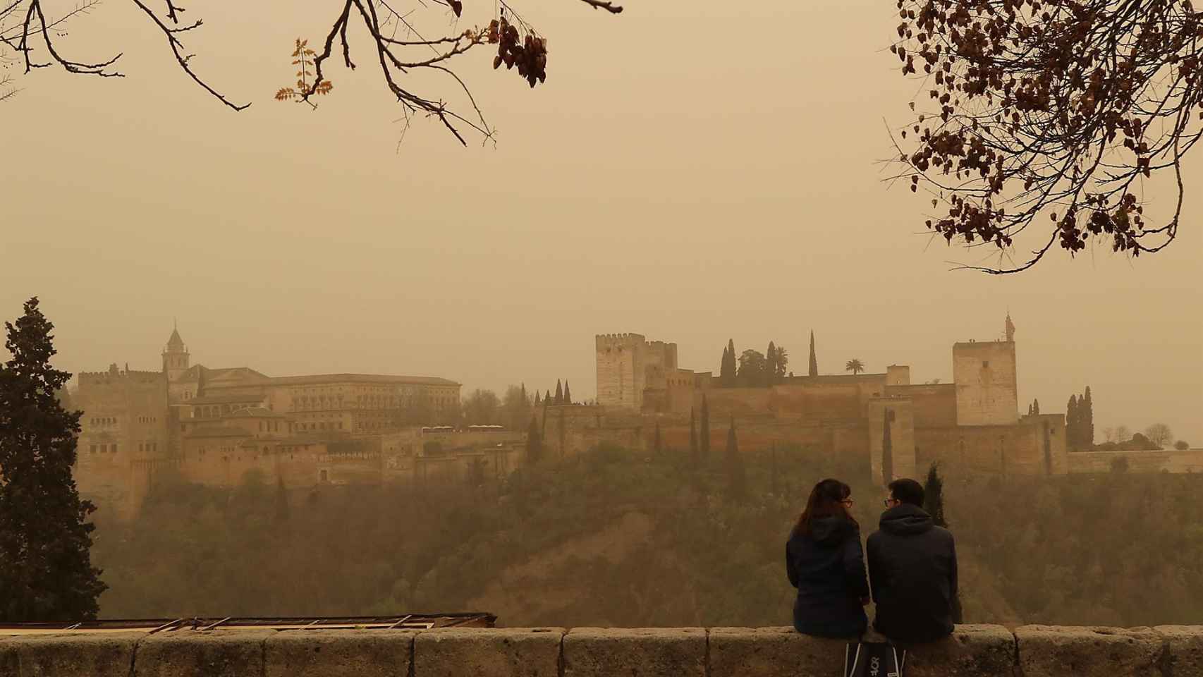 Dos personas observan la Alhambra desde el Mirador de San Nicolás.
