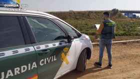 Agente de la Guardia Civil junto a su vehículo.