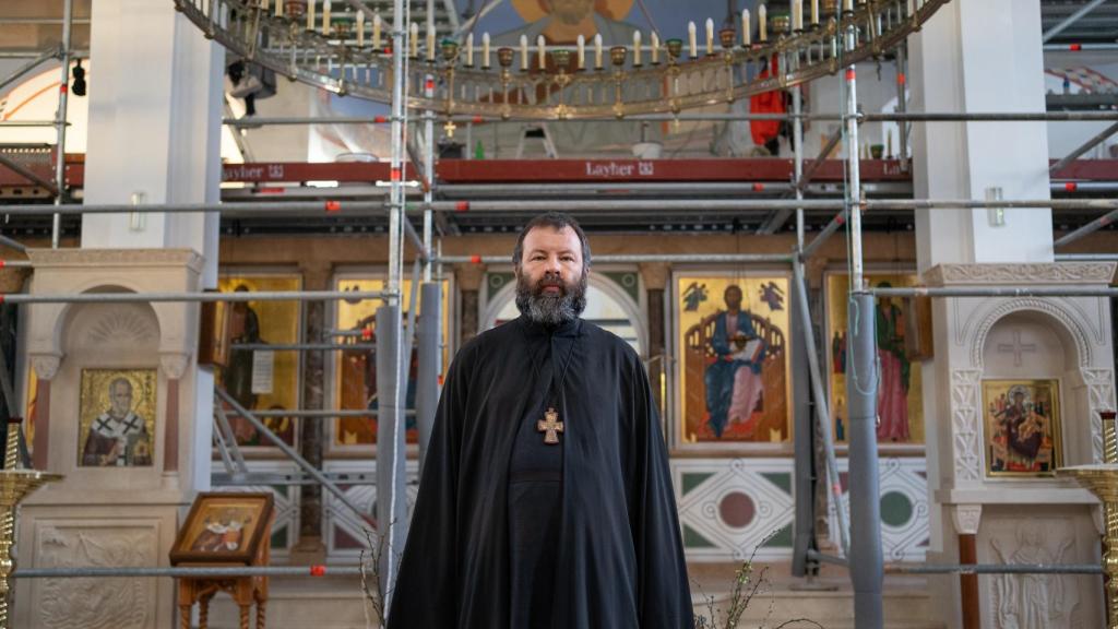 El padre Kórdochkin, con los andamios de fondo en la catedral ortodoxa.