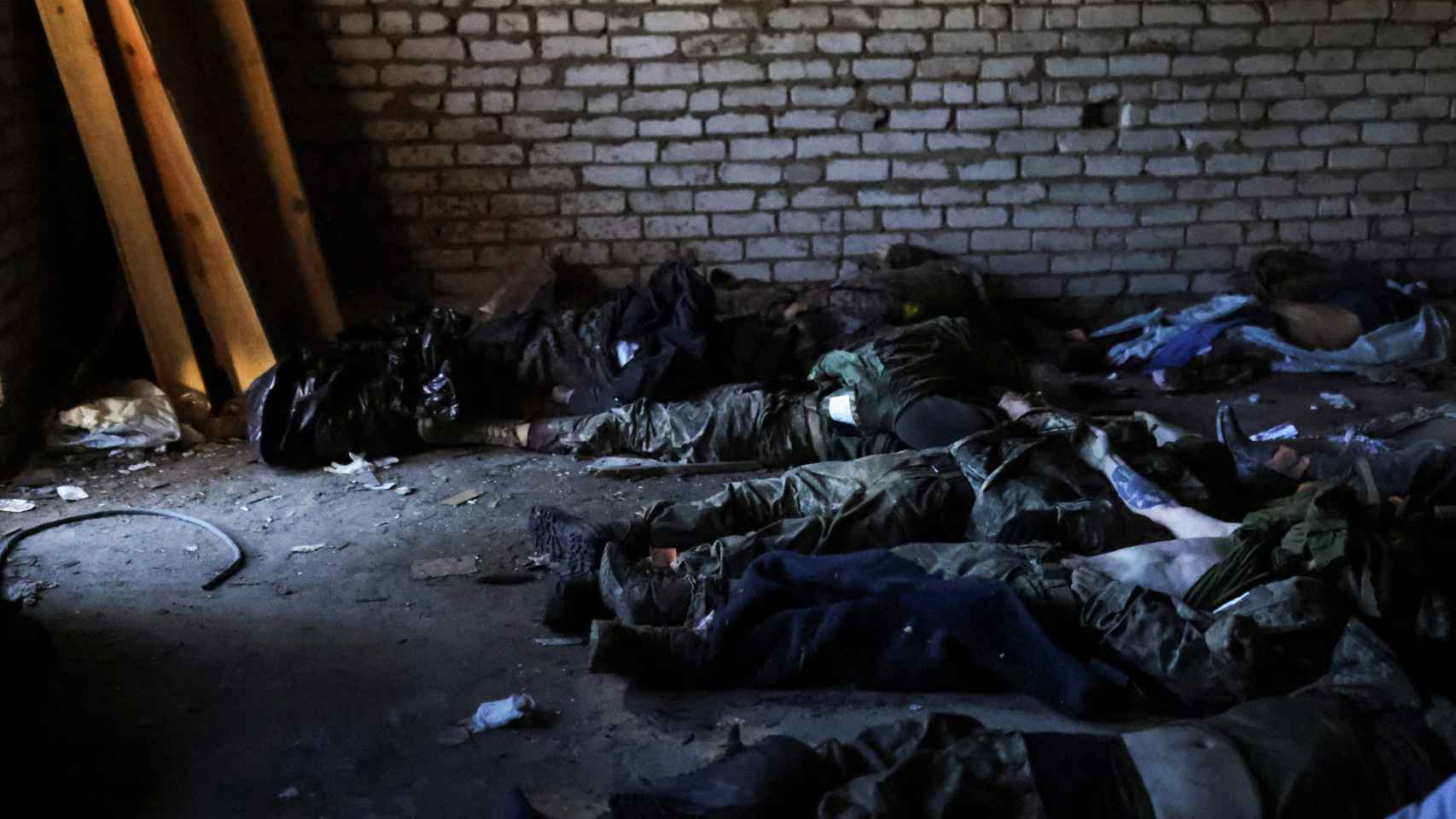 Soldados y civiles ucranianos muertos en los combates esperan a que sus familias vayan a reclamarlos en un edificio también bombardeado.