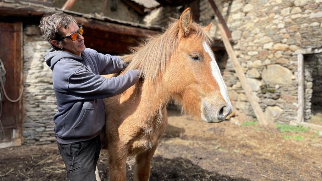 Renau acaricia a Aska, una de sus dos jóvenes yeguas. También, cuenta con otros animales como perros o gallinas.