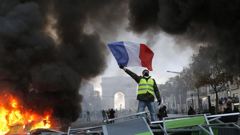 Un manifestante ondea la bandera de Francia en los Campos Elíseos, durante las protestas de noviembre de 2018.