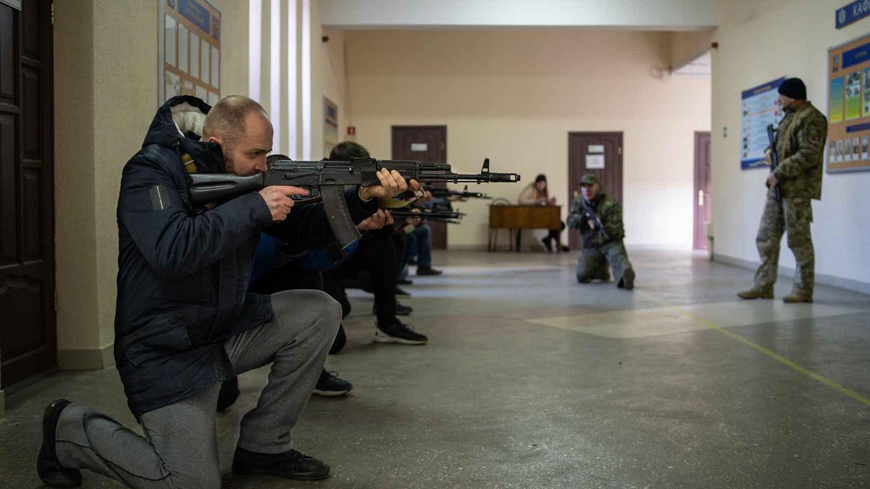 En los pasillos del segundo piso, dos militares enseñan las posiciones básicas con un arma entre las manos.
