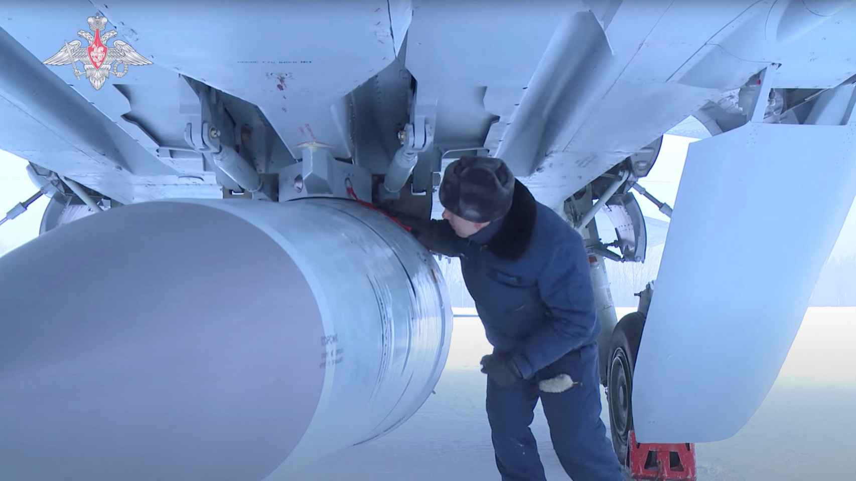 Un soldado ruso revisa un misil hipersónico sujeto a un caza de combate.