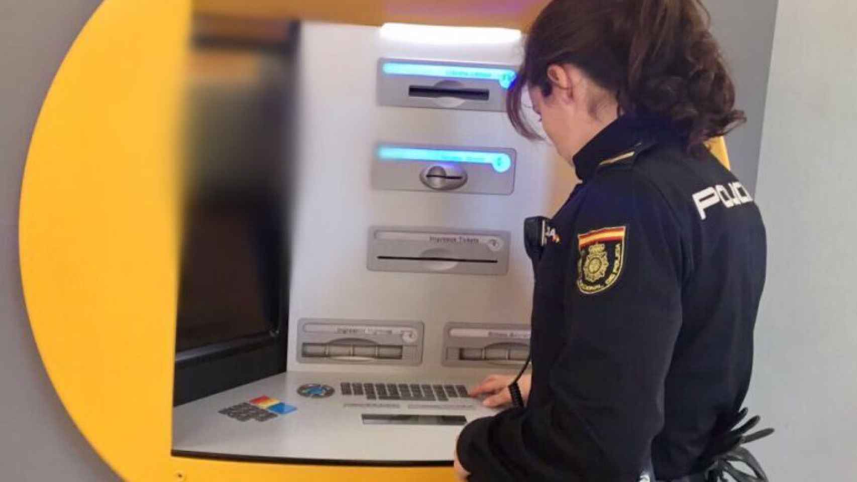 Una Policía Nacional revisa un cajero automático. Archivo