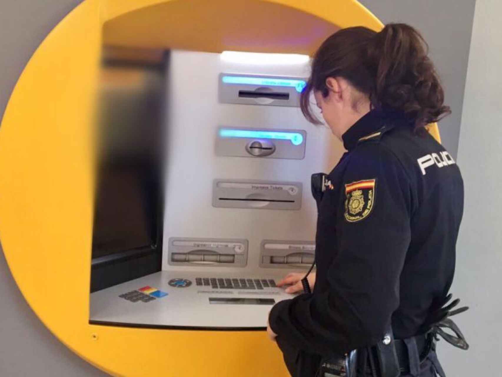 Una Policía Nacional revisa un cajero automático