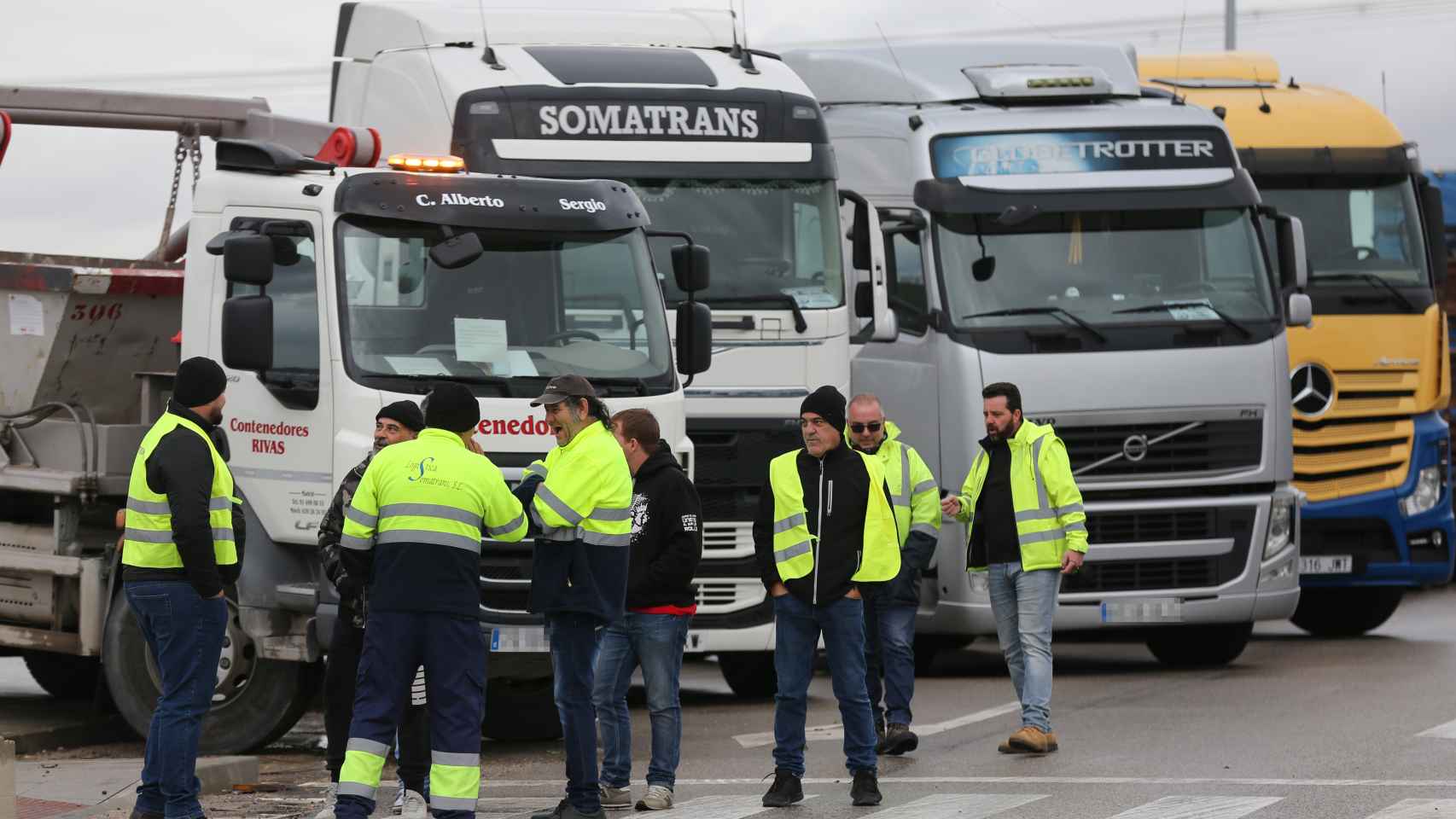Un grupo de transportistas delante de sus camiones.