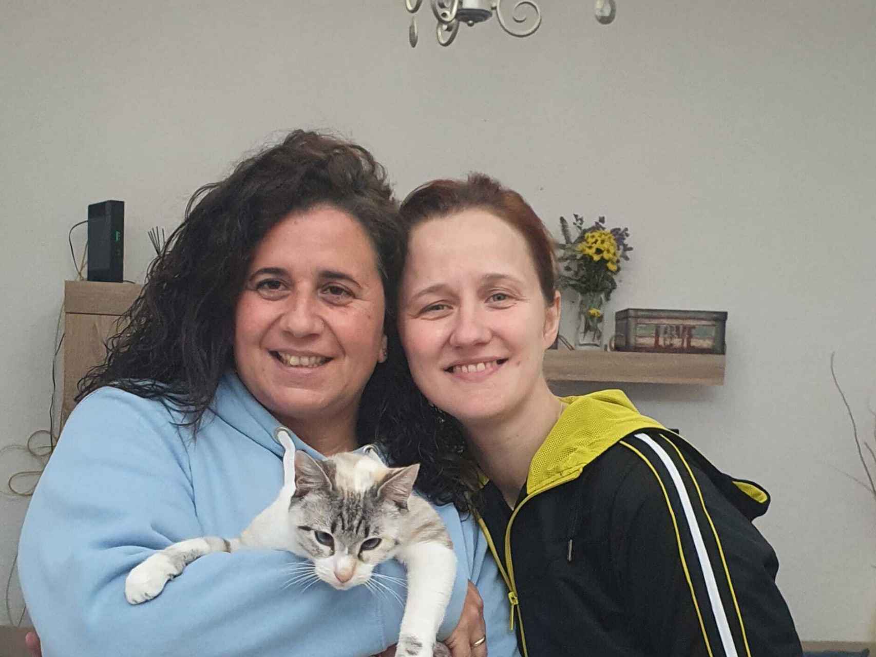 Rocío y Vika, las dos madres de esta familia de 12, posan con la gata.