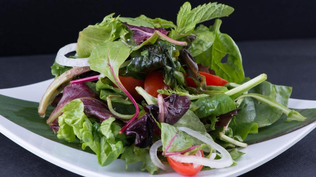 Una ensalada verde con tomate y cebolla.