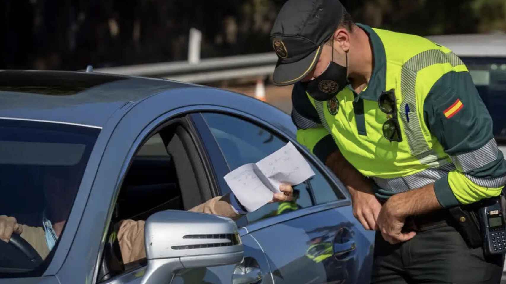 Un guardia civil revisando los papeles de un conductor.